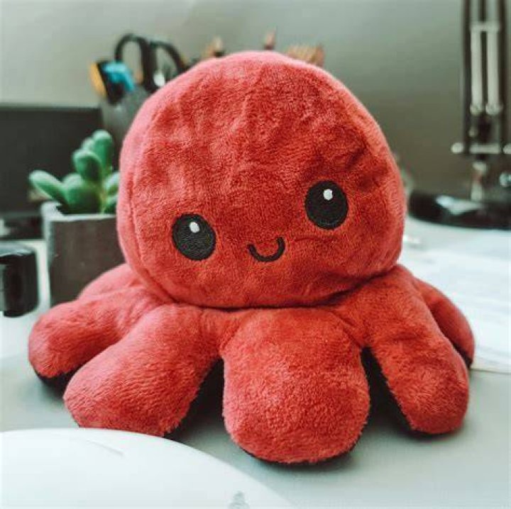 a red stuffed animal sitting on top of a bed